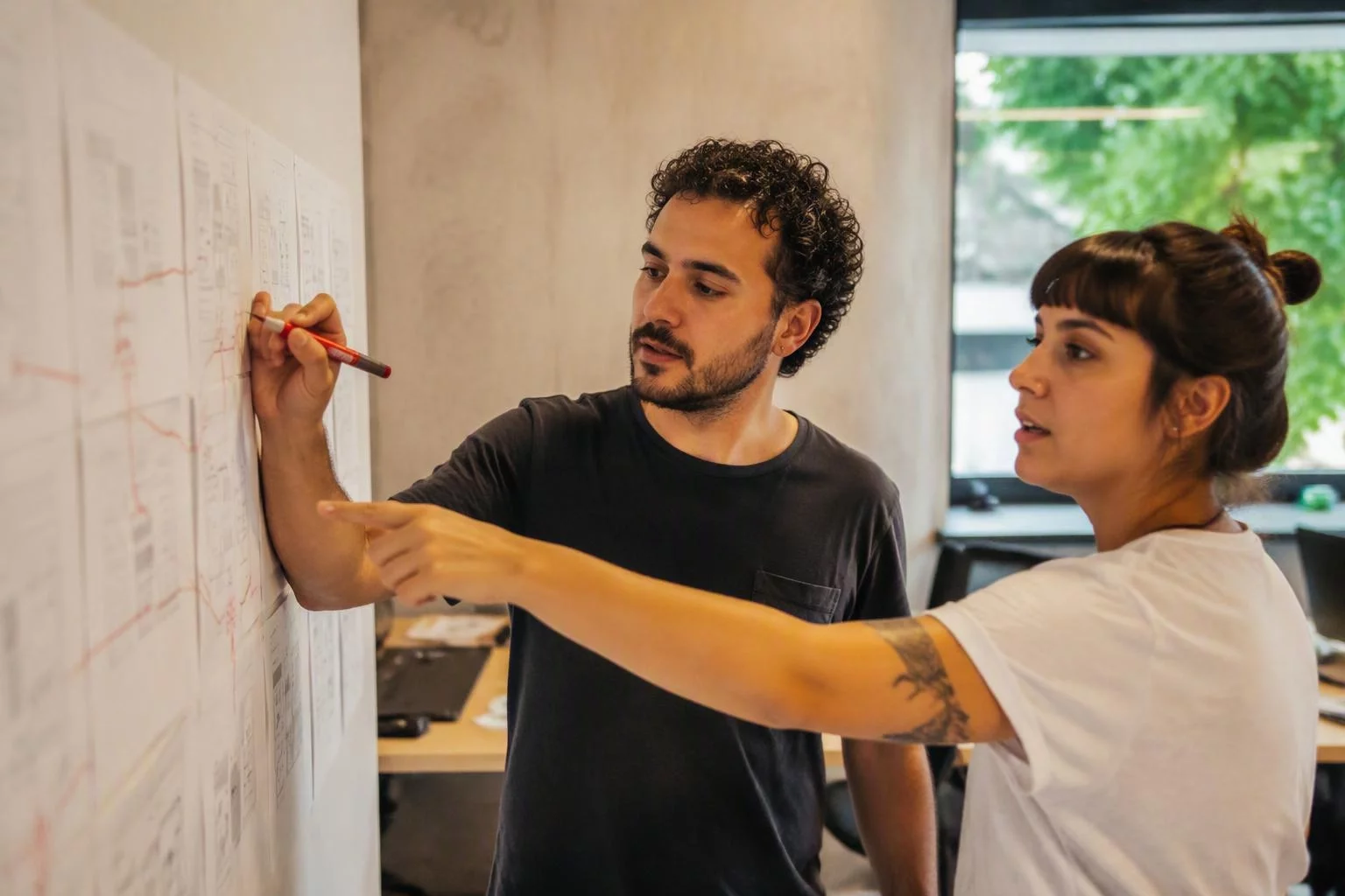 Dupla desenhando o percurso de um produto em folhas presas na parede